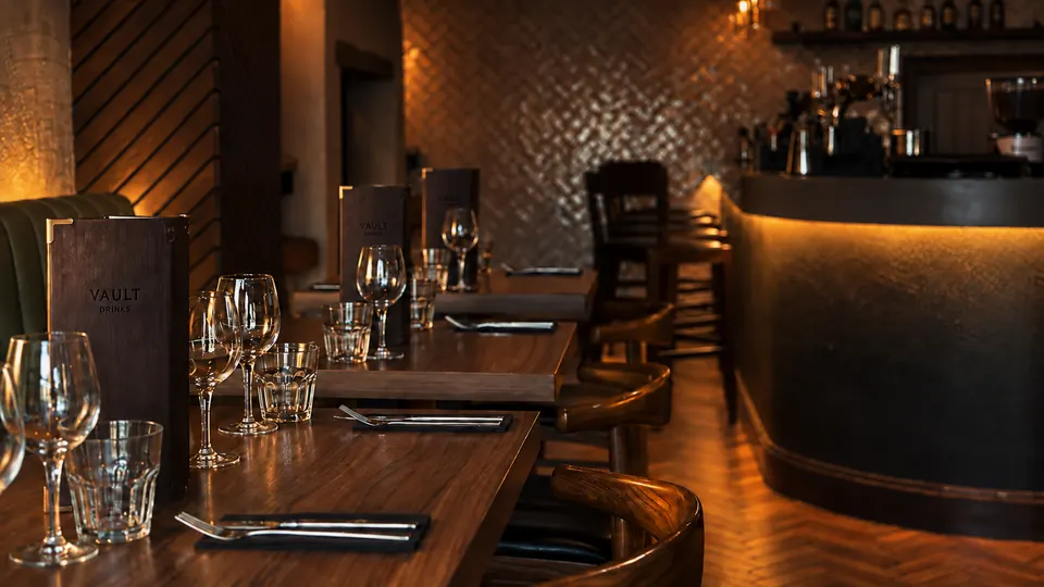 Tables laid in the bar at Vault Bar + Kitchen, Whalley, looking towards the counter